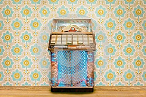 Colorful vintage jukebox in front of retro flower wallpaper photo