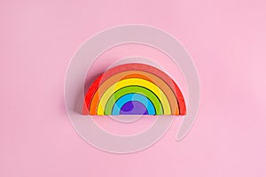 Colorful Waldorf wooden rainbow in a montessori teaching pedagogy on pink background, kid play concept