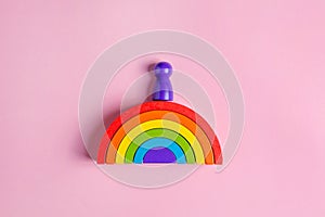 Colorful Waldorf wooden rainbow in a montessori teaching pedagogy on pink background, kid play concept