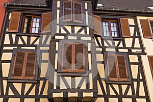 Colorful wall of old half-timbered house with multiple windows and wooden shutters, close-up
