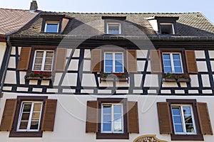 Colorful wall of old half-timbered house with multiple windows and wooden shutters, close-up