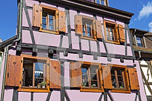 Colorful wall of old half-timbered house with multiple windows and wooden shutters