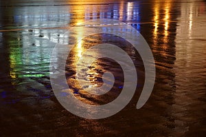 Colorful water reflection on the road. City lights reflected in puddle.