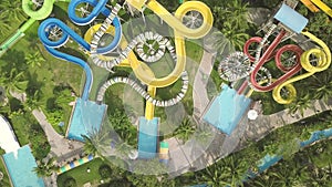 Colorful water slide in amusement aquapark. Aerial view. People having fun riding on slides in outdoor water park at