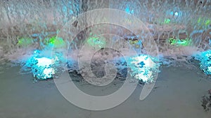 Colorful water in the waterfall. decorative fountain at night. The fountain is illuminated with colorful lights.