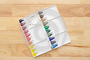 Colorful watercolor paints set in watercolor palette on wood