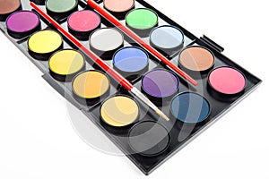 Colorful watercolors paints in palette with brushes isolated on