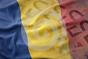 Colorful waving national flag of romania on a euro money banknotes background.