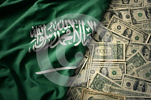 colorful waving national flag of saudi arabia on a american dollar money background. finance concept