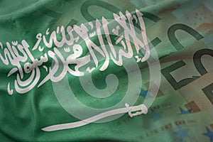 Colorful waving national flag of saudi arabia on a euro money banknotes background.