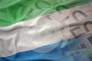 Colorful waving national flag of sierra leone on a euro money banknotes background.