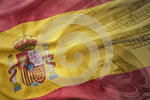 Colorful waving national flag of spain on a american dollar money background.