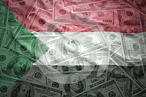 Colorful waving sudanese flag on a dollar money background
