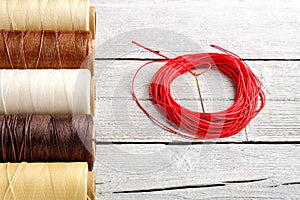 Colorful wax cord, leather thread on white wooden background for leather crafting, wicker work and handcrafts.