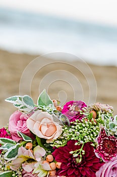 Colorful wedding bouquet from roses. Pink, red and green. Beach wedding.