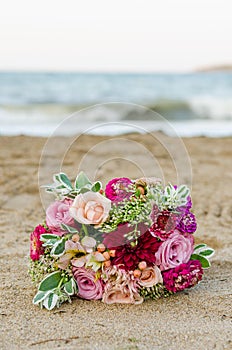 Colorful wedding bouquet from roses. Pink, red and green. Beach wedding.