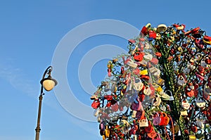 Colorful wedding padlocks on a metal tree against blue sky