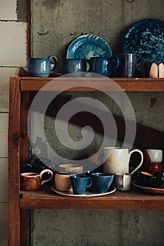 Colorful, white and blue ceramic cups and dishes on shelves of pottery store