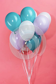 Colorful white, blue and purple decorative festive balloons on pink background.