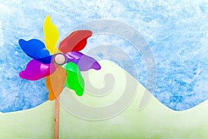 Colorful windmill toy on green hills