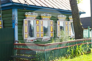 Colorful windows with carved platbands on the decorated facade of the wooden house. Belarus