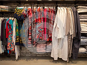 colorful women clothing dress, wardrobe and t-shirts hang on hangers inside of shopping mall