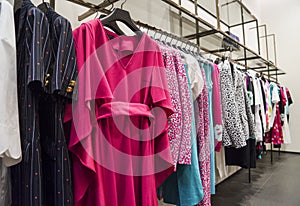 Colorful Women`s dresses on hangers in a fashion store. Shop stylish clothes, close-up. - image.