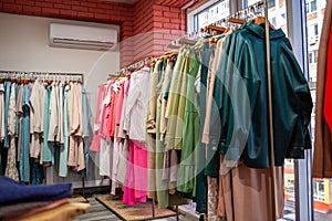 Colorful women's dresses on hangers in a retail shop.