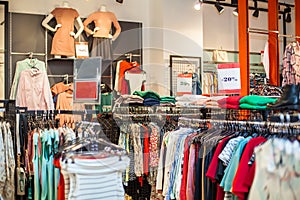 Colorful women`s dresses on hangers in a retail shop. Fashion and shopping concept