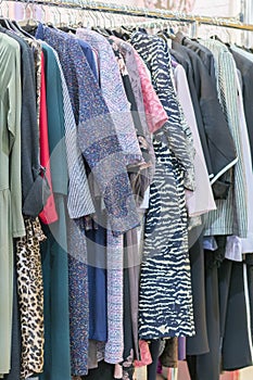 Colorful women`s dresses on hangers in a retail shop. Fashion and shopping concept. Hanger with clothes in the store