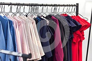 Colorful women`s dresses and other clothes on hangers in a retai