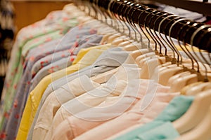 Colorful women`s shirts on hangers in a retail shop. Fashion and shopping concept