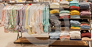 Colorful women`s shirts on hangers in a retail shop. Fashion and shopping concept