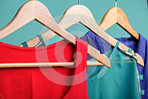 Colorful women`s shirts on wood hangers on blue background. RGB