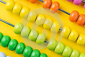 Colorful wooden abacus beads on vivid yellow background, business financial or accounting profit and loss concept, or use in educ