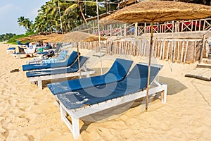 colorful wooden beach umbrellas and sunbeds loungers on sandy beach of ocean