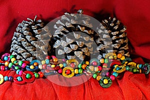 COLORFUL WOODEN BEADS WITH DRY CONES ON RED DRAPE