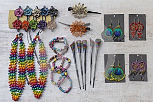 Colorful wooden beads necklace, bracelets, hairpins and earrings on white wooden background, close up