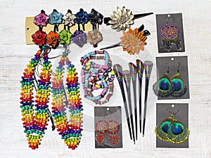 Colorful wooden beads necklace, bracelets, hairpins and earrings on white wooden background