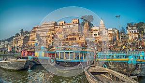 Colorful wooden boats docked along the shore of the Ganges River, at one of the many ghats in Varanasi, India.