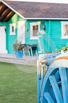 Colorful wooden bungalow with old blue wooden wagon.