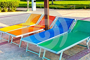 Colorful wooden chaise lounges in swimming pool