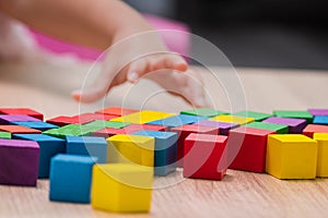 Colorful wooden cube block on table, child hand`s playing it