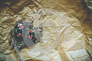 Colorful wooden easter eggs and wooden fanny rabbit on a craft paper background. Toned