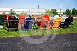 Colorful wooden lawn chairs set up outside to be sold in the fond du Lac, Wisconsin area during the summer for people to buy.