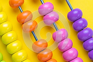 Colorful wooden pink and orange abacus beads on yellow background, business financial or accounting profit and loss concept, or u