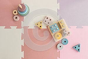 Colorful wooden stacking toys on pink play mat in nursery room