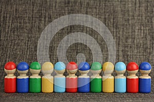 Colorful wooden toy people are lined up in a row, brown cloth or fabric  background with copy space