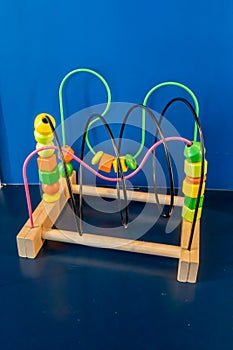 Colorful wooden toy stand alone on dark blue shelf against blue wall