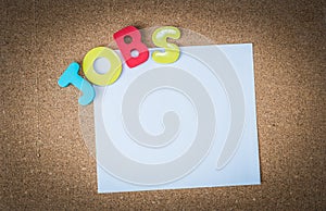 Colorful Wooden word JOBS with White paper on cork board